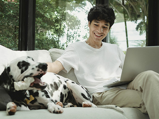 Happy man sitting with his dog on a couch, represents how individual therapy in Deerfield, Il can help break negative patterns and improve your self-esteem.