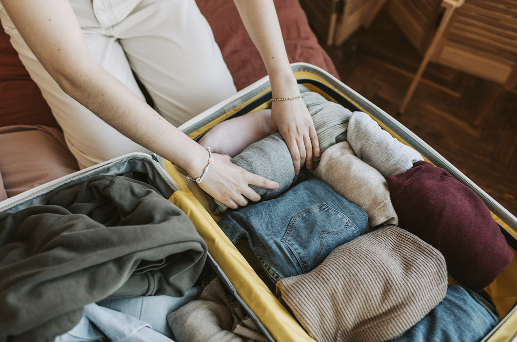 Person carefully packing a bag one of the steps of the plan to leaving an abuse relationship safely.