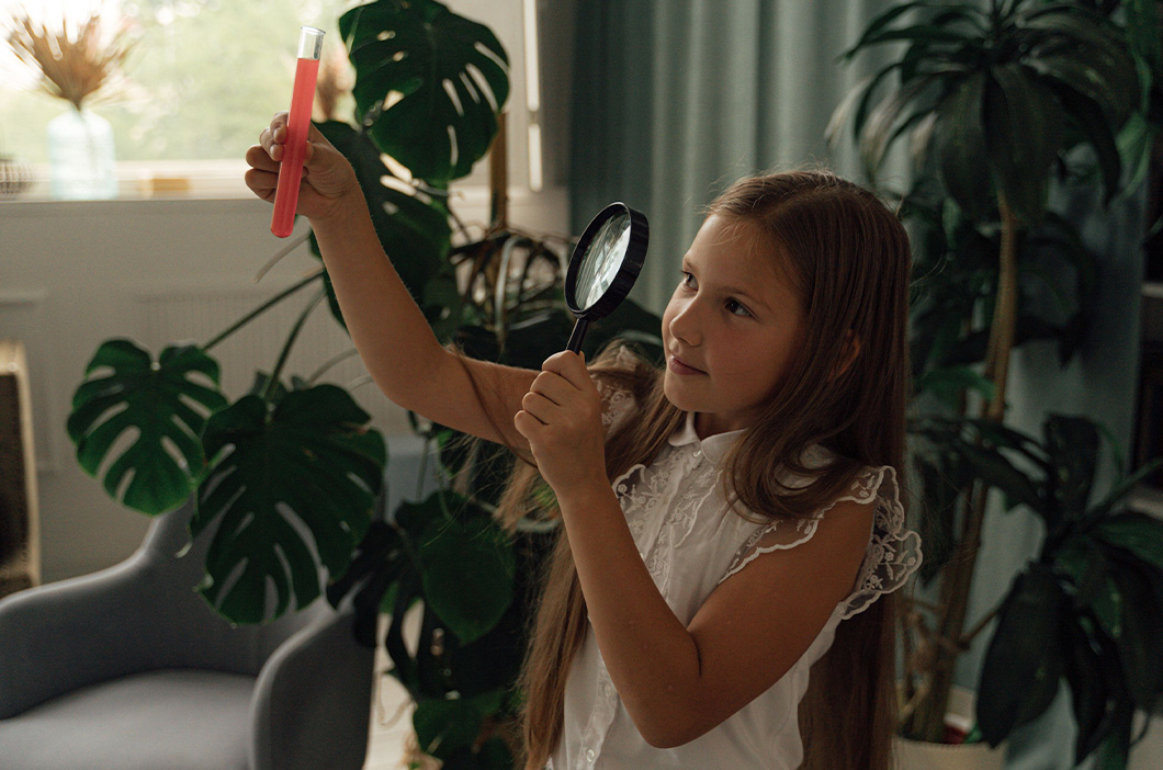 Girl looking at a test tube through a magnifying glass, represents the spark of the curiosity in why our therapist Brenda Kendziera became a counselor.